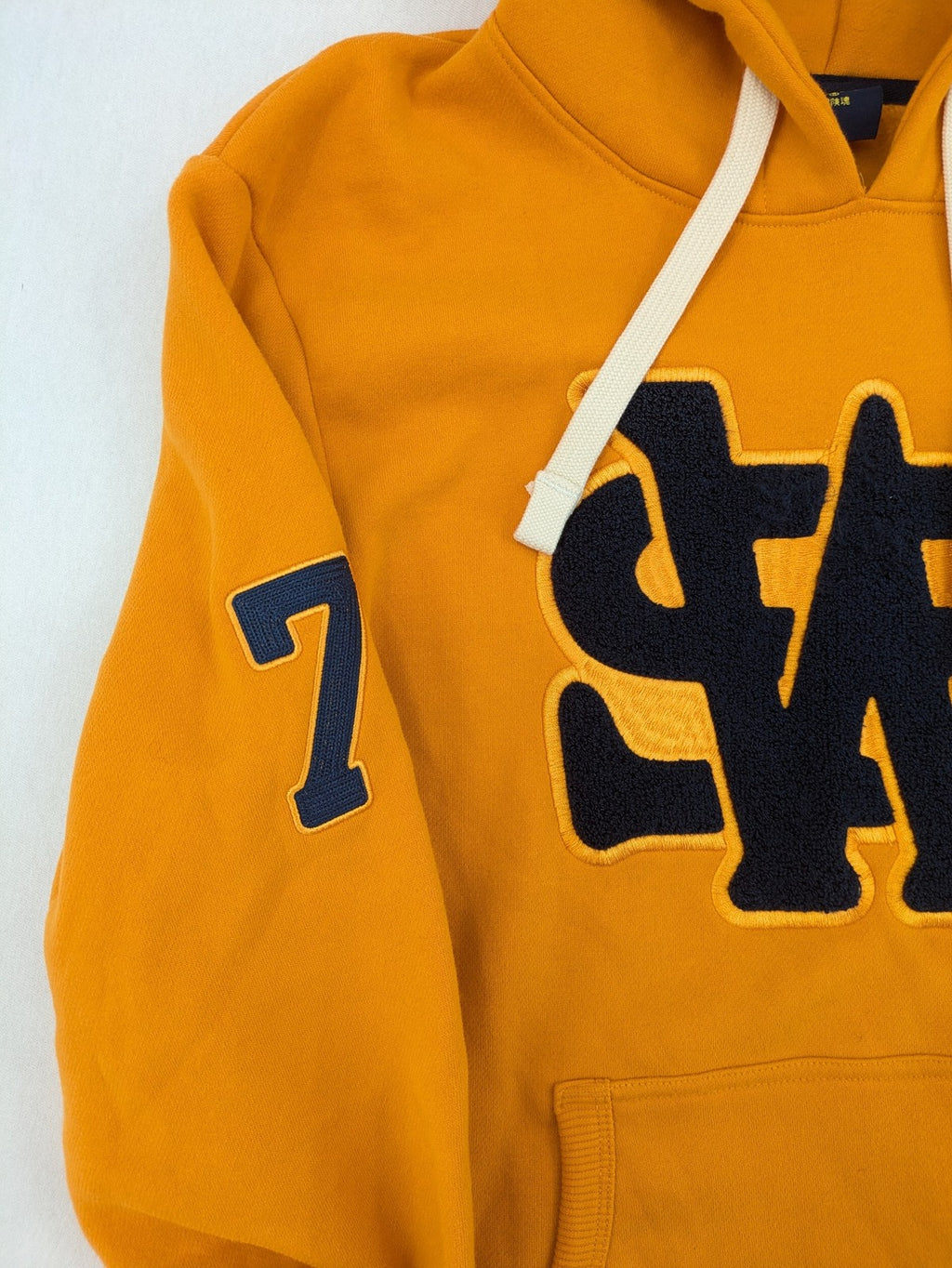 Superdry orange turtle neck jumper with textured logo patch and number 7 detail.