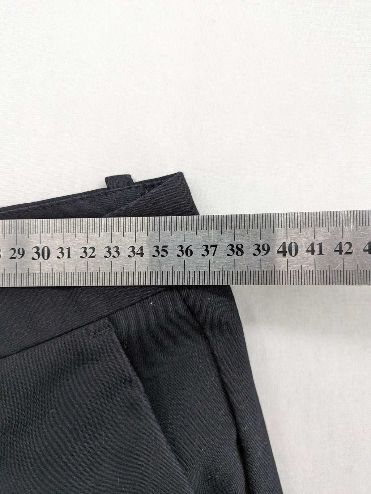 Zara black pants with front creases, subtle slit hem, and buttoned back pocket.
