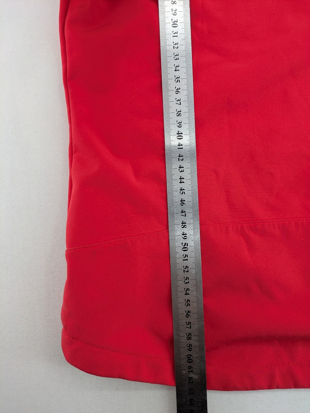 Pinea red softshell jacket with adjustable hood and fleece lining, multiple zippered pockets.