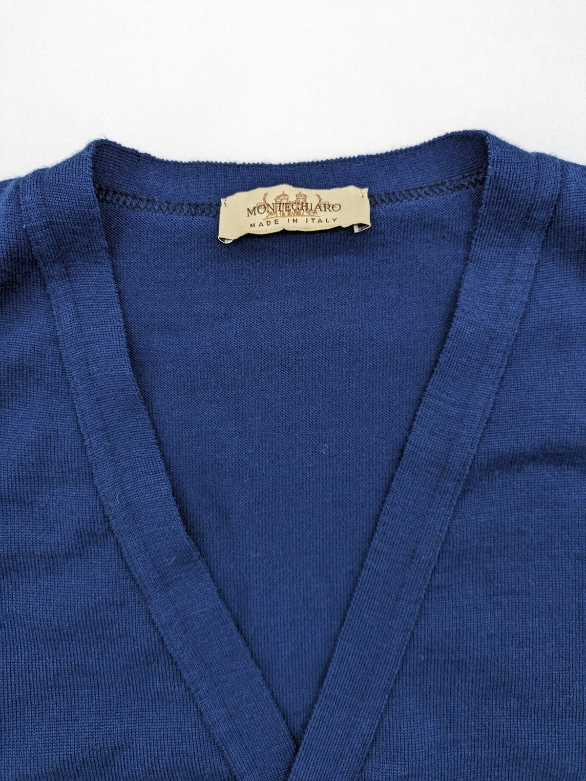 Montechiaro blue turtle neck jumper with V-neck, button placket, and sleeveless design.