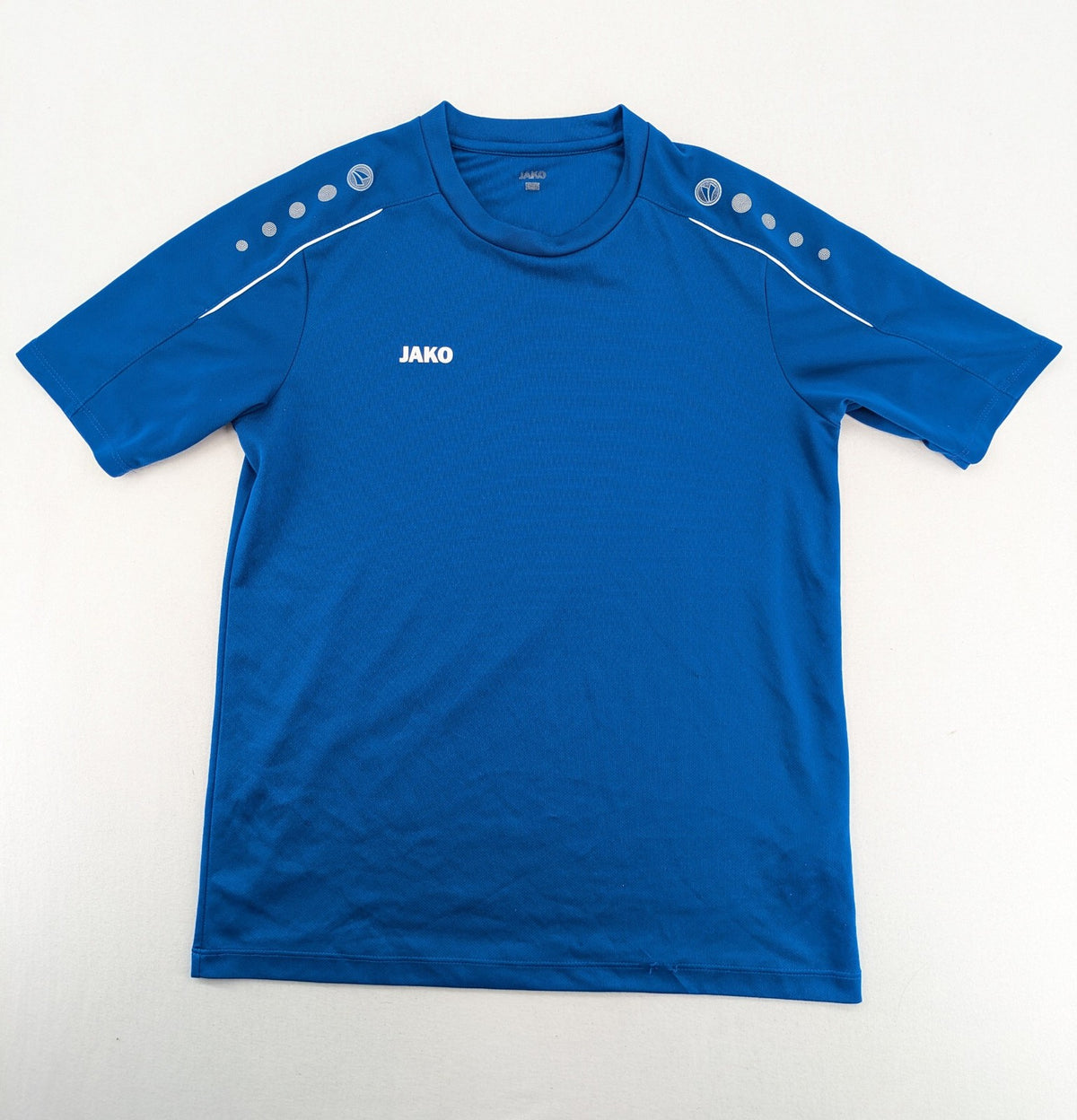 Jako blue short-sleeve training shirt with logo details and breathable polyester material.