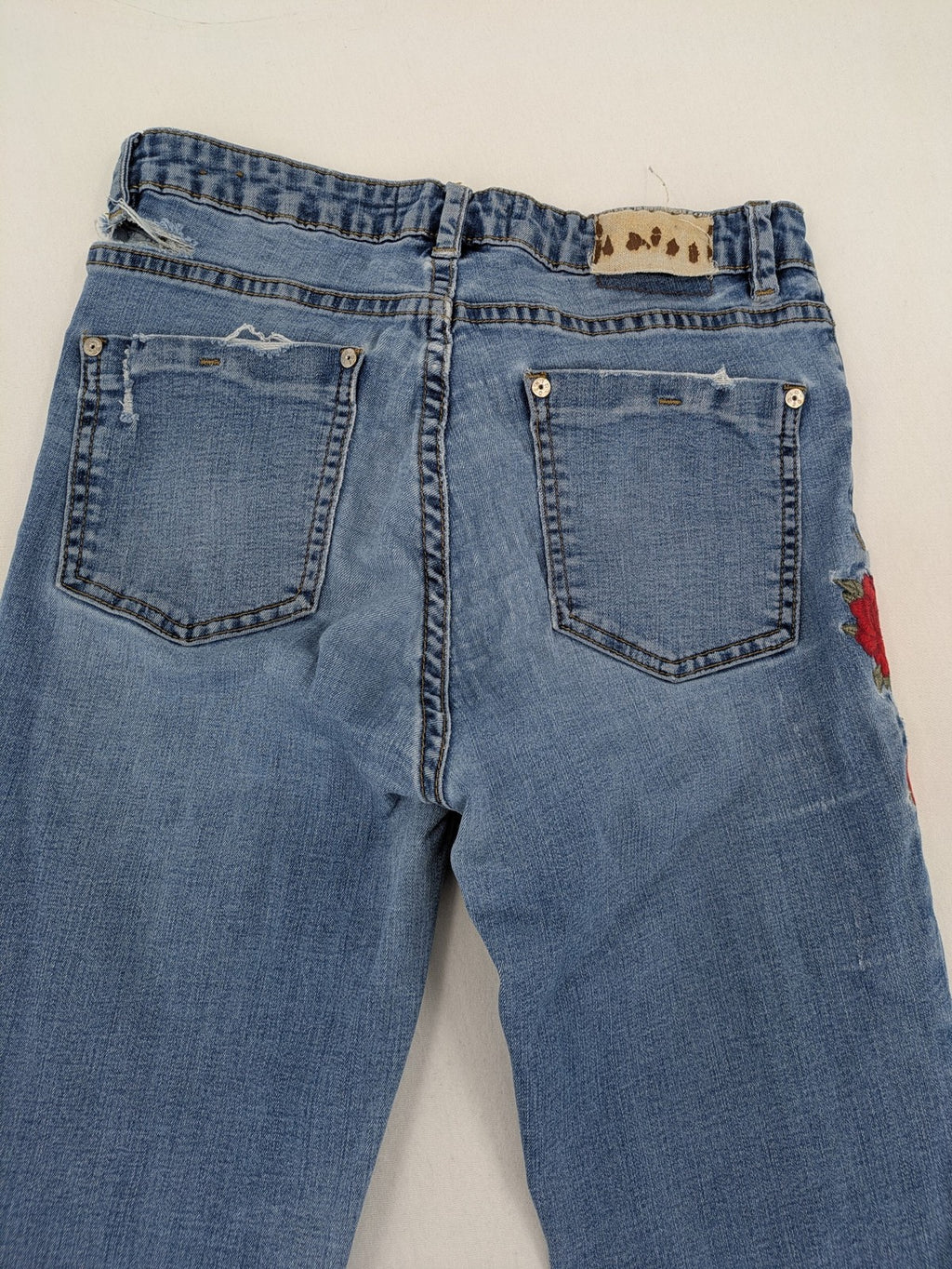 Jennyfer pink skinny jeans with distressed details and red rose embroidery on hips and knees.