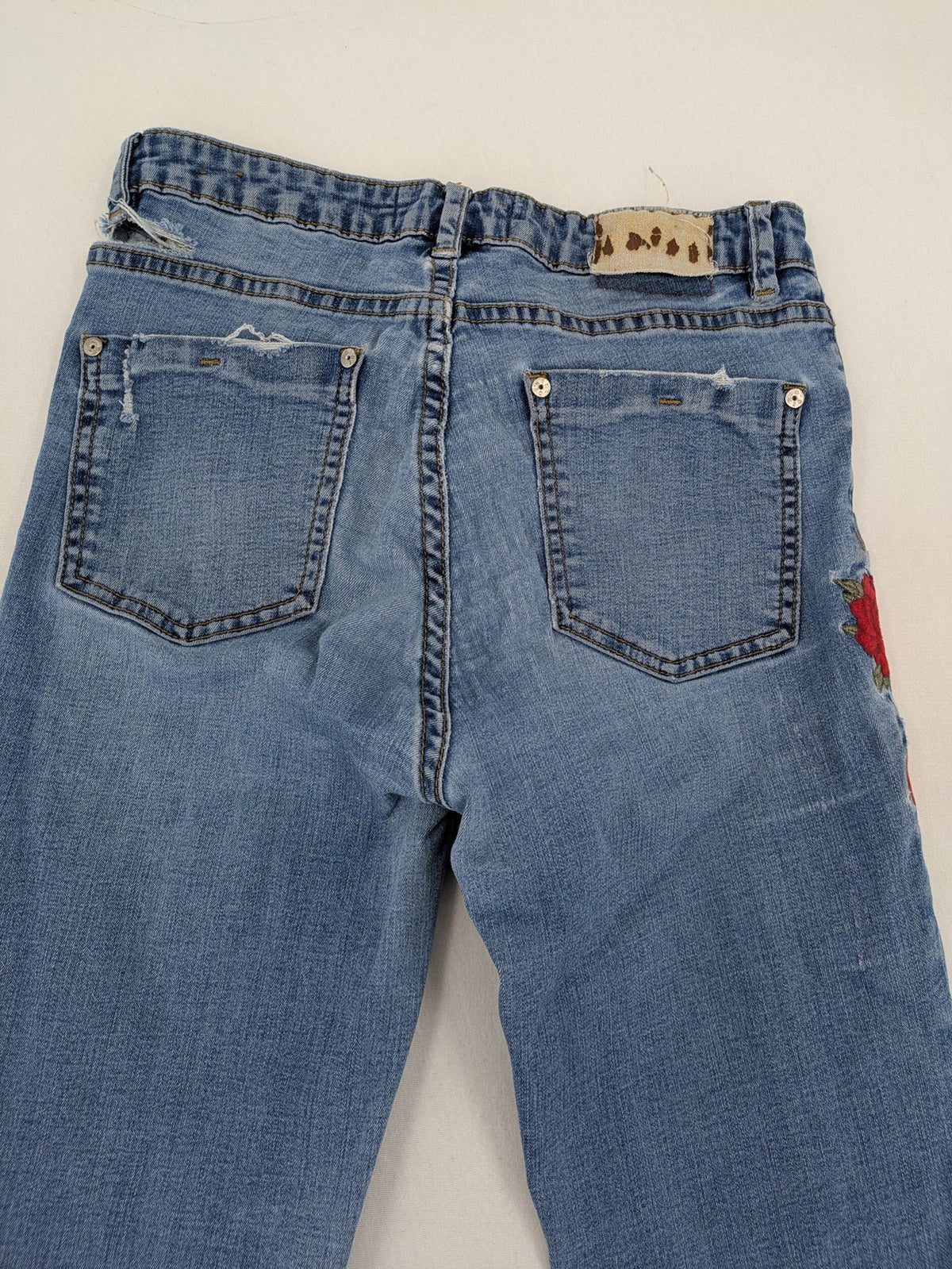 Jennyfer pink skinny jeans with distressed details and red rose embroidery on hips and knees.