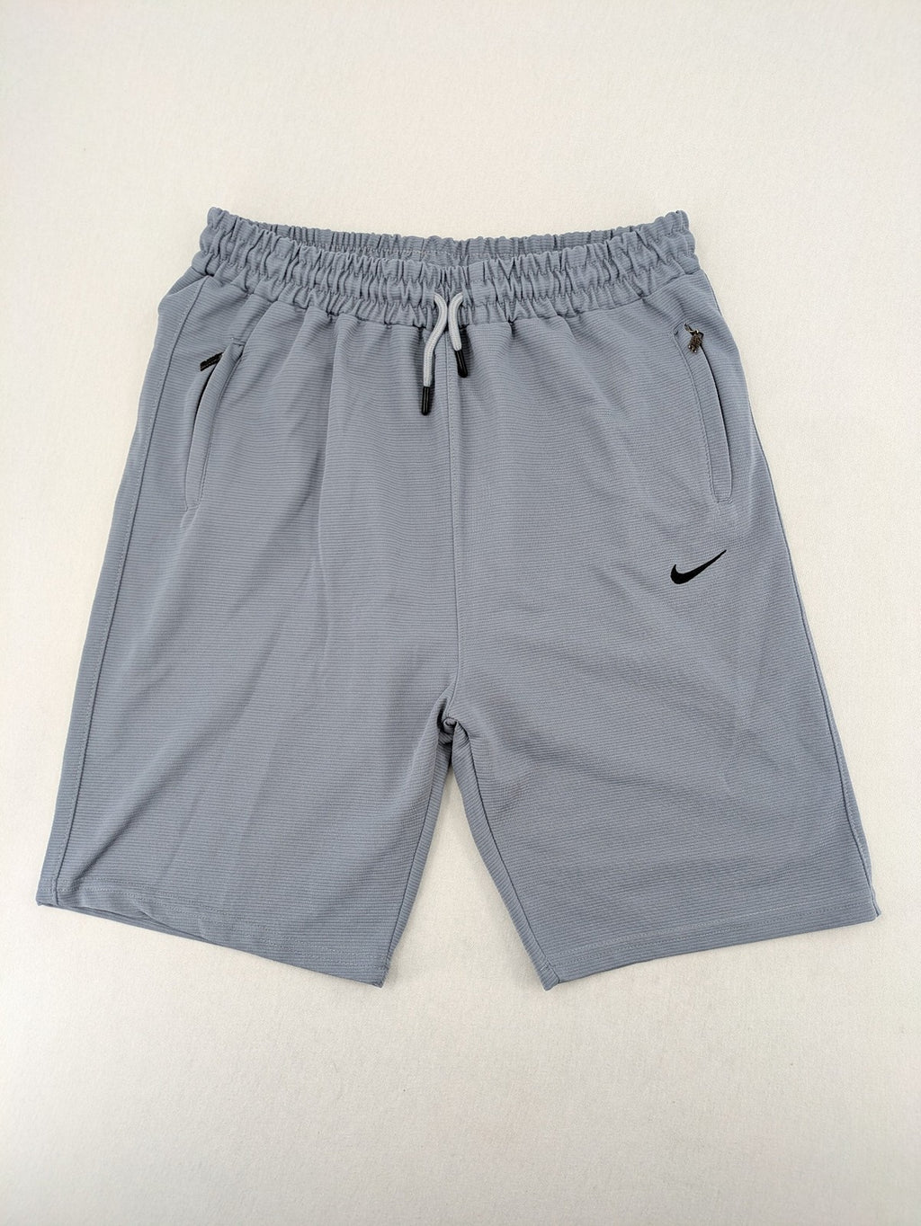 Nike grey shorts with Dri-FIT technology, elastic waistband, and zippered pockets.