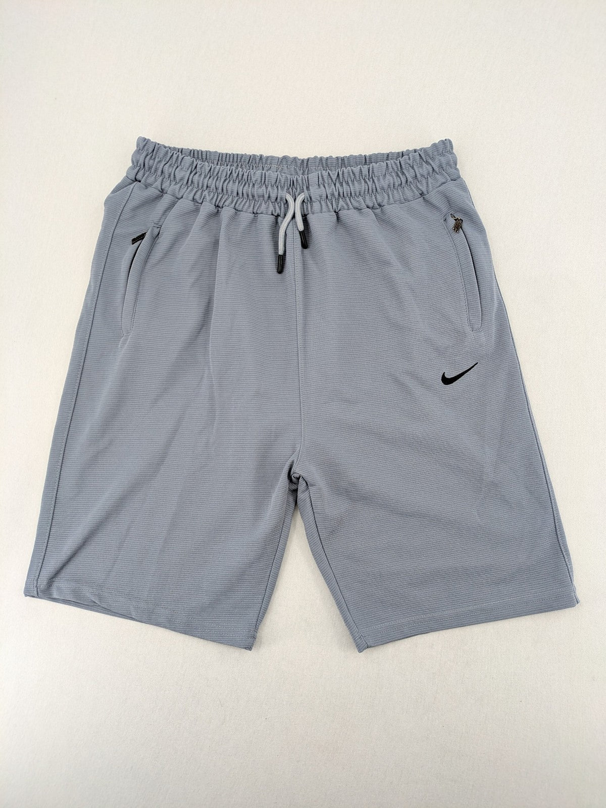 Nike grey shorts with Dri-FIT technology, elastic waistband, and zippered pockets.