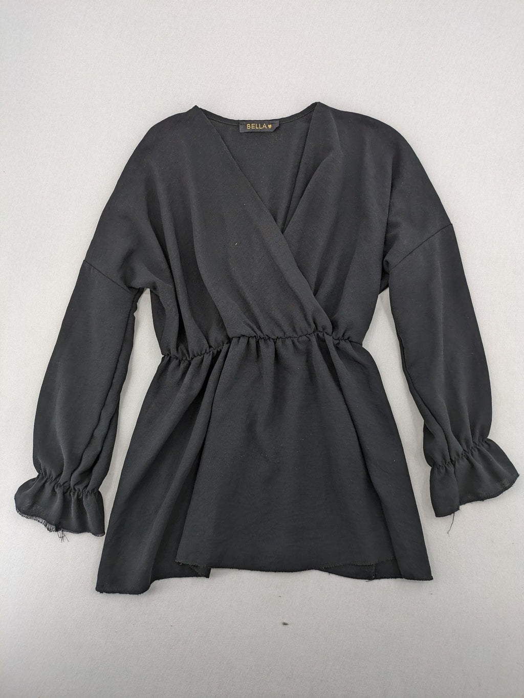 Bella black wrap blouse with deep V-neck and ruffled long sleeves.