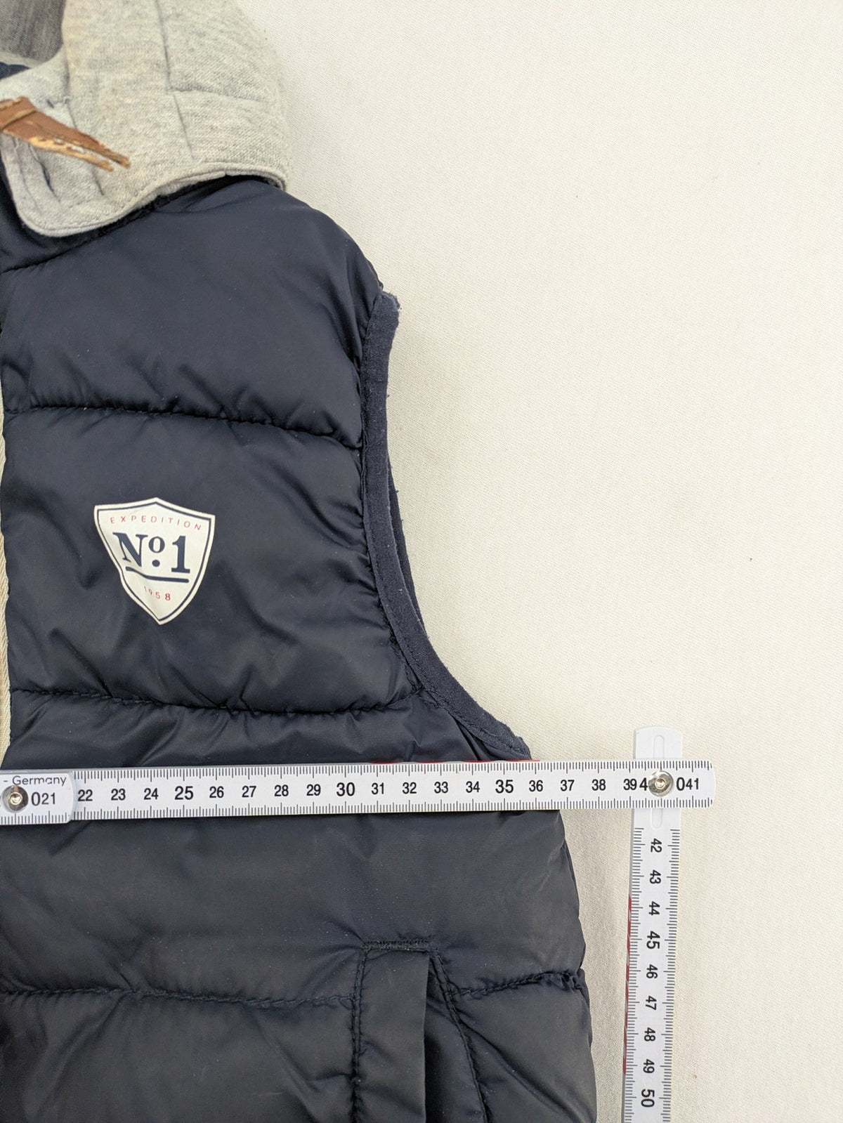 H&M navy puffer vest with grey hood and zip pockets for kids.