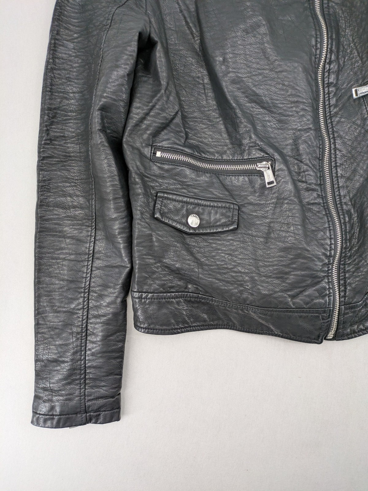 Guess black faux leather biker jacket with asymmetric zipper and multiple zip pockets.