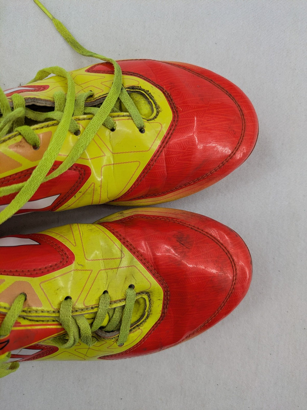 Adidas F50 soccer shoes red and yellow with three-stripe logo and lightweight synthetic material.