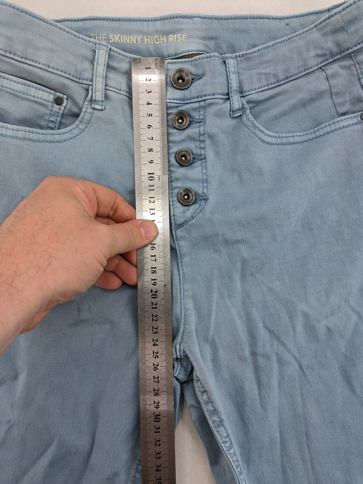 Yessica blue skinny jeans high rise with button fly and V-cut hem detail.