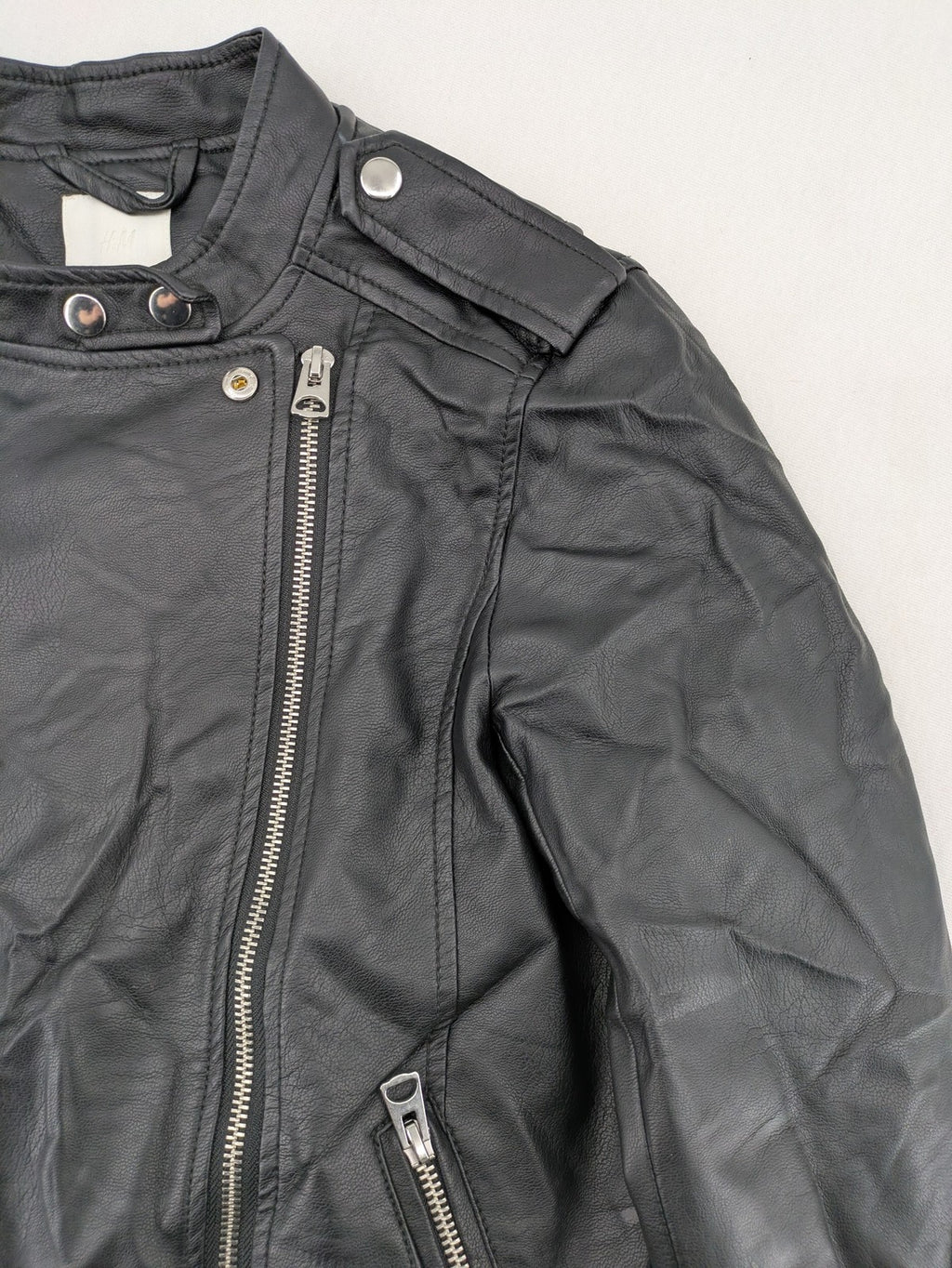 H&M black biker jacket with silver zippers, shoulder flaps, and snap-button details.