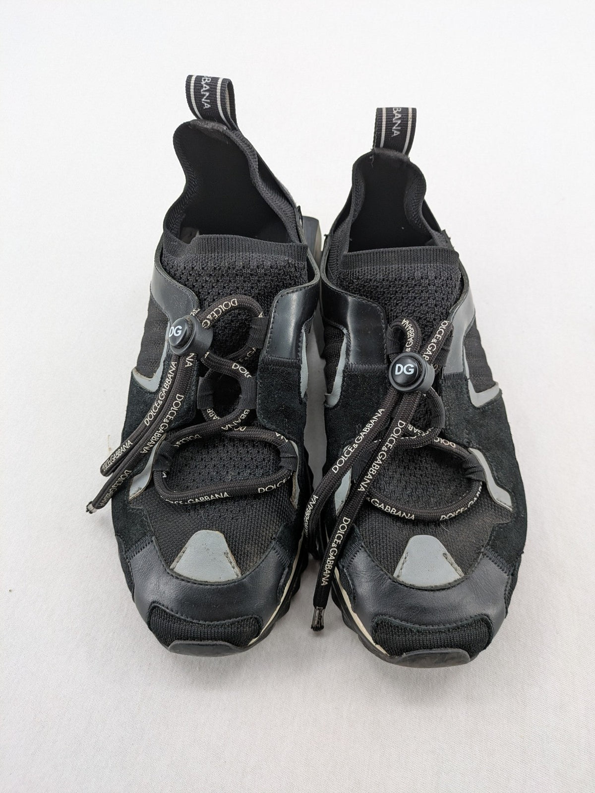 Dolce & Gabbana black sneakers with logo laces and segmented sole design.