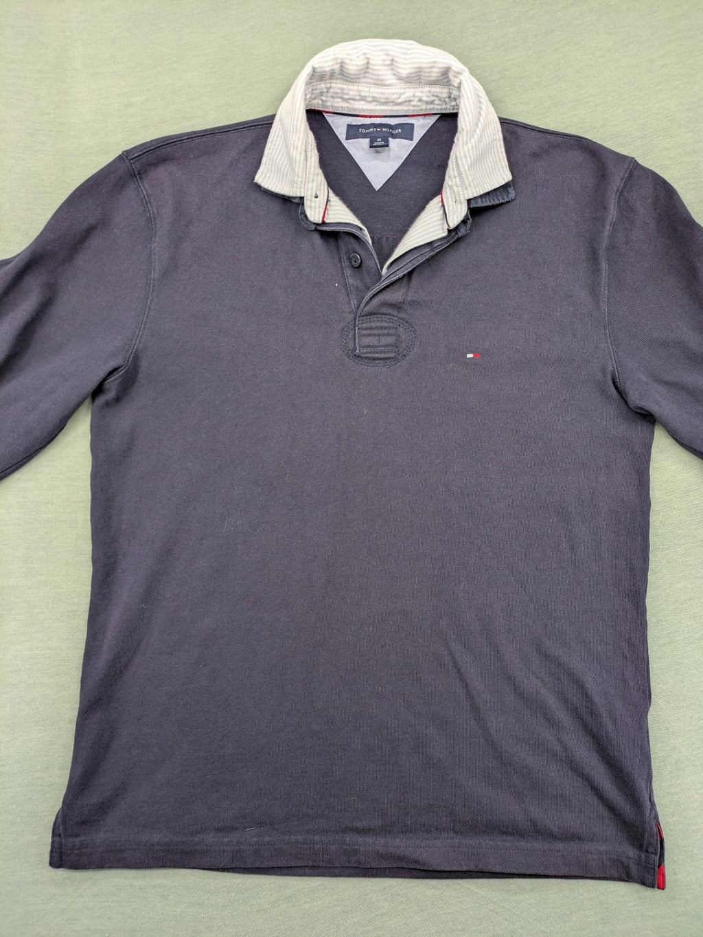 Tommy Hilfiger grey rugby polo shirt with navy striped collar and large H logo.