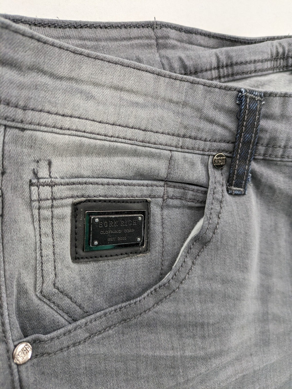 Born Rich grey slim fit jeans with button fly and washed denim texture.
