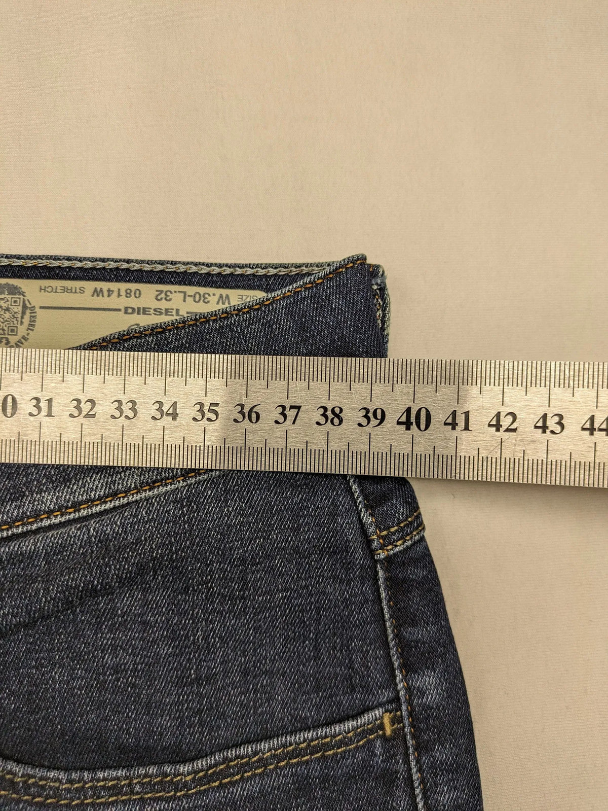 Diesel blue straight jeans with regular waist, dark wash, and stretch material.
