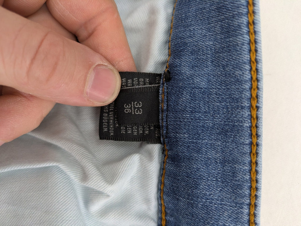 Drykorn blue straight jeans with stretch denim, classic fit, and logo patch on waistband.