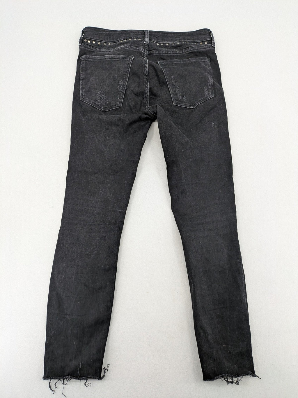 Zara Woman black skinny jeans with distressed details, silver studs, and frayed hem.