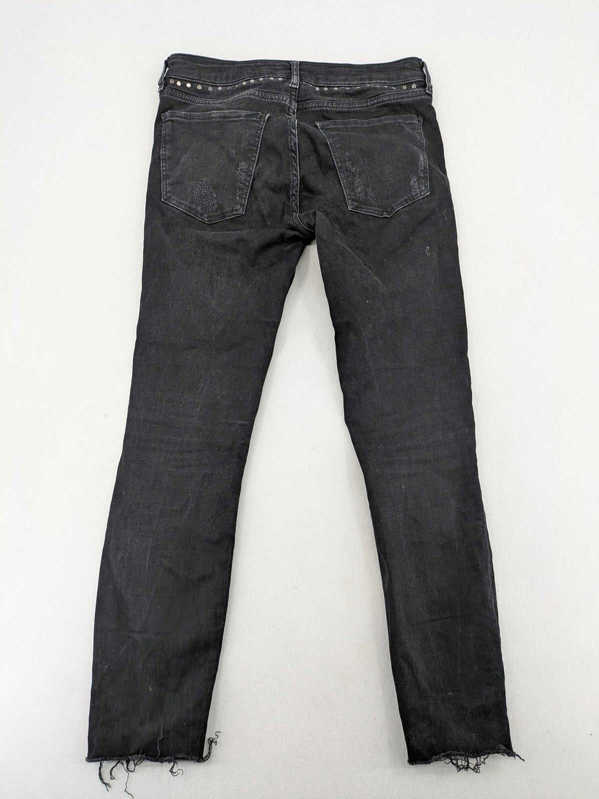 Zara Woman black skinny jeans with distressed details, silver studs, and frayed hem.
