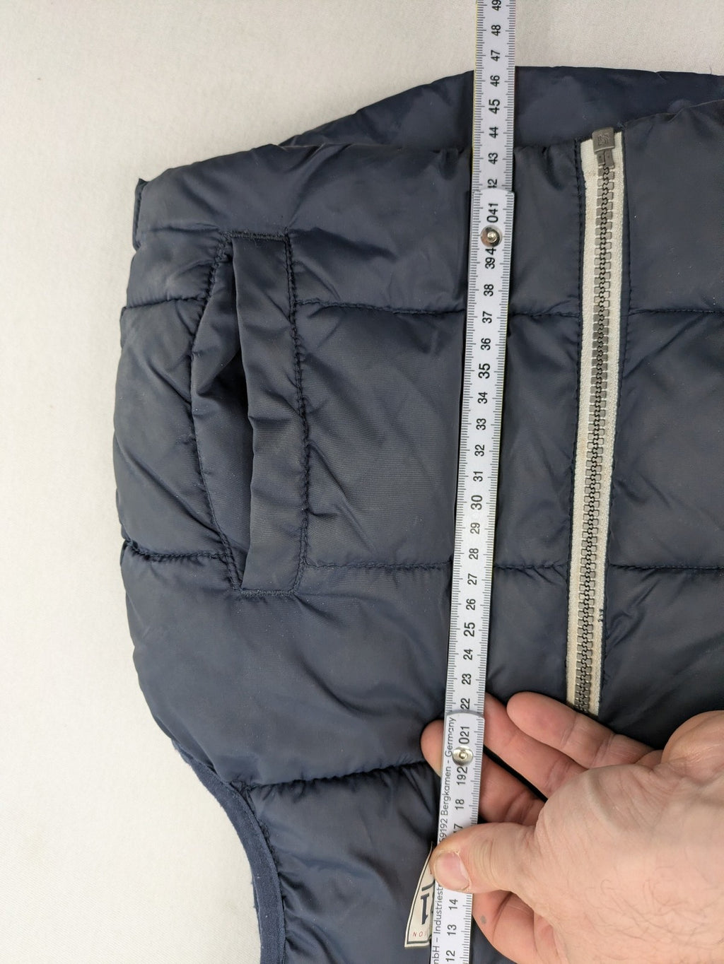 H&M navy puffer vest with grey hood and zip pockets for kids.