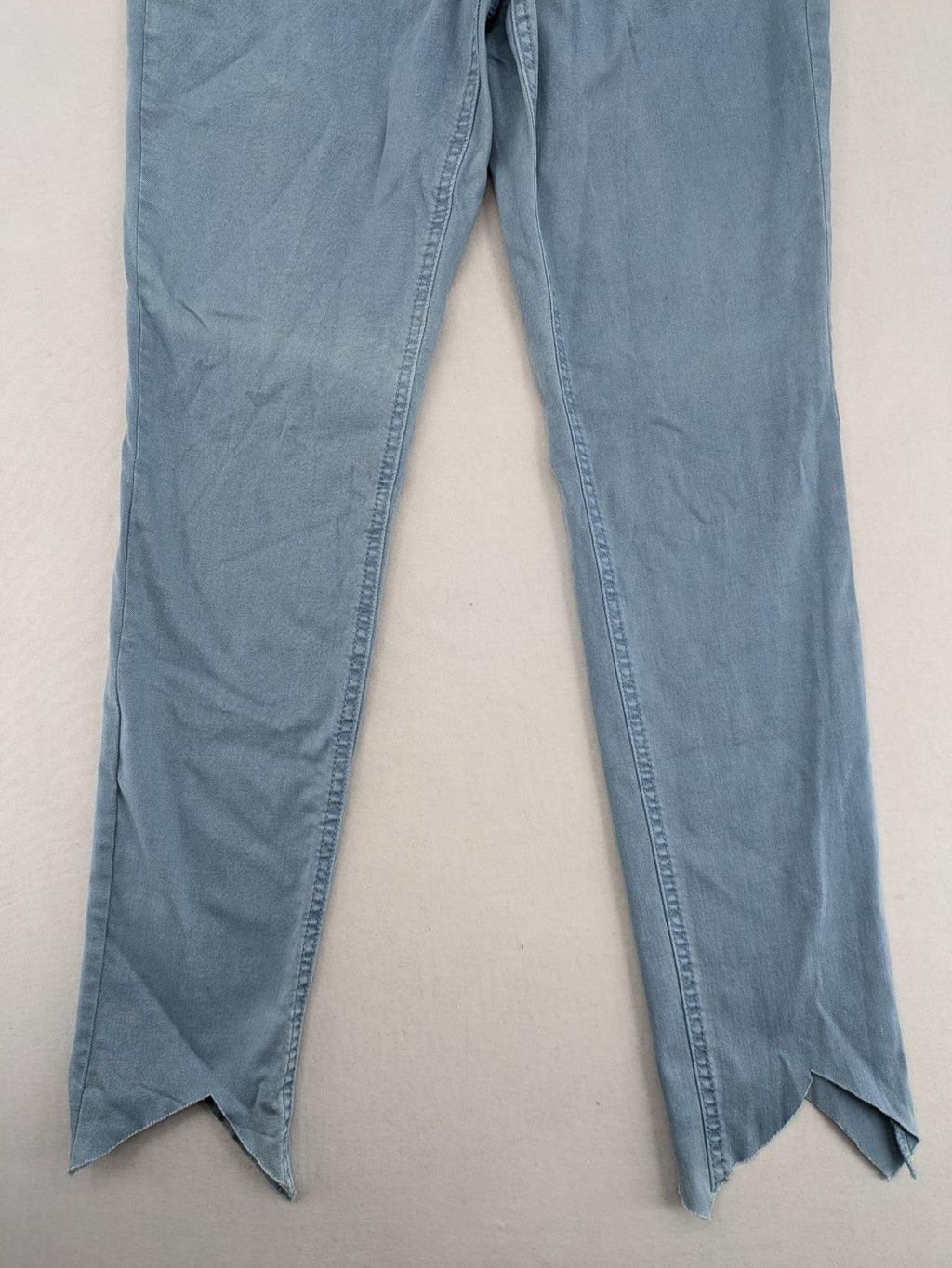 Yessica blue skinny jeans high rise with button fly and V-cut hem detail.
