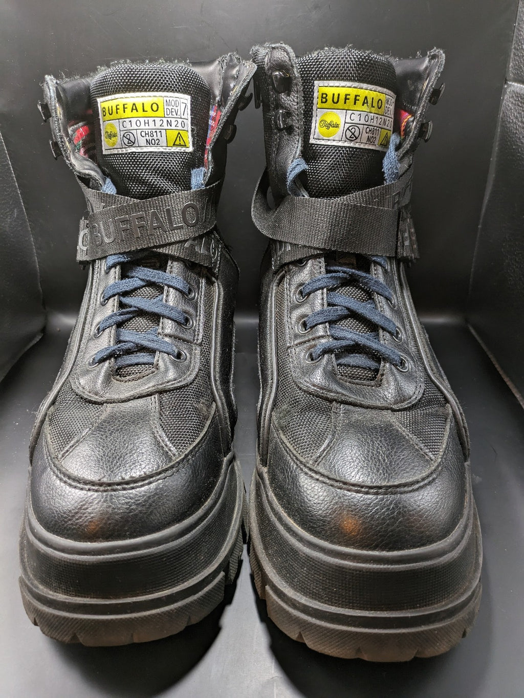 Buffalo black motorcycle boots with chunky sole, adjustable buckle strap, and red plaid lining.