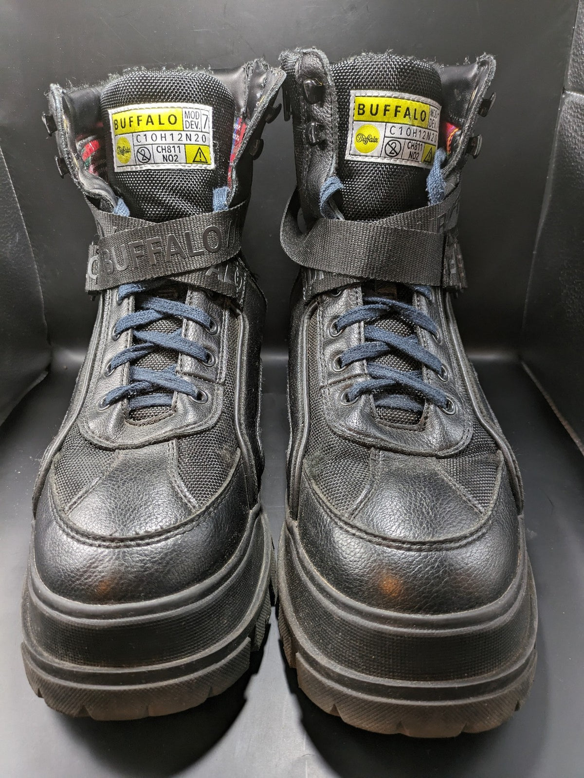 Buffalo black motorcycle boots with chunky sole, adjustable buckle strap, and red plaid lining.
