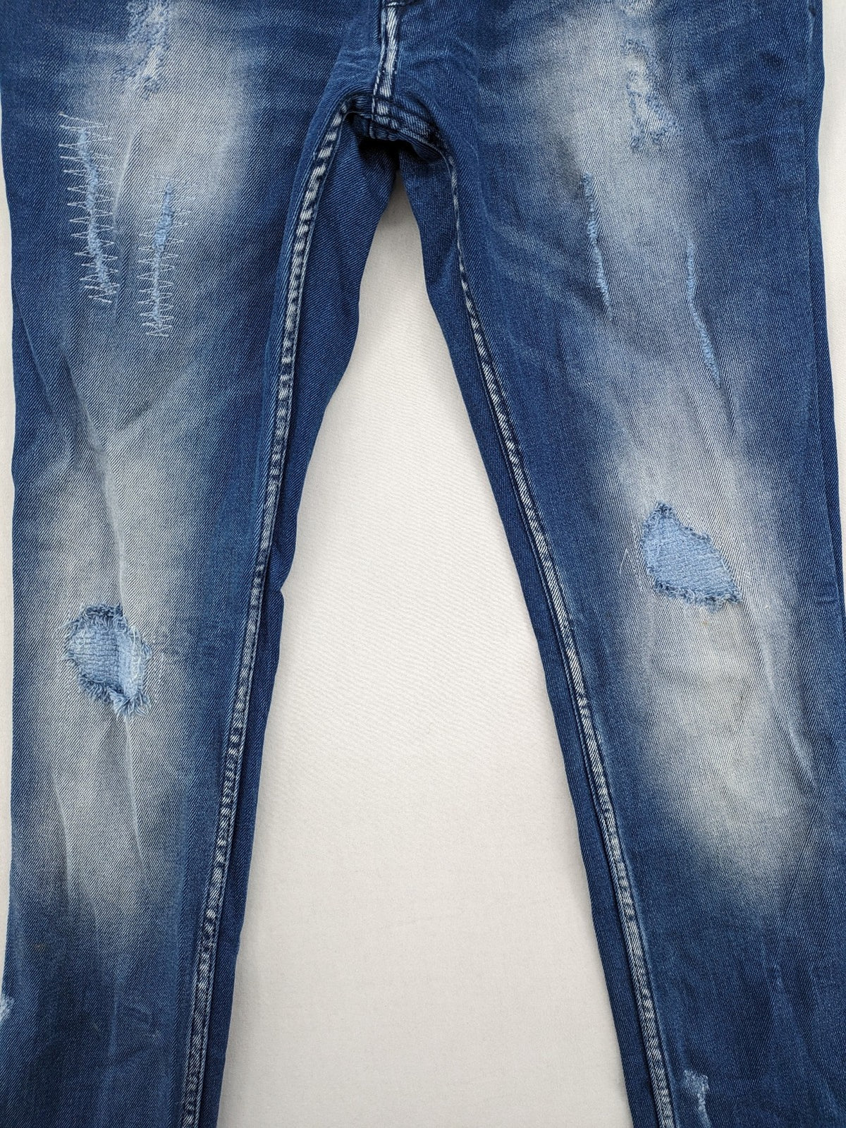 Diesel blue straight jeans with distressed details and ripped accents, made of cotton.