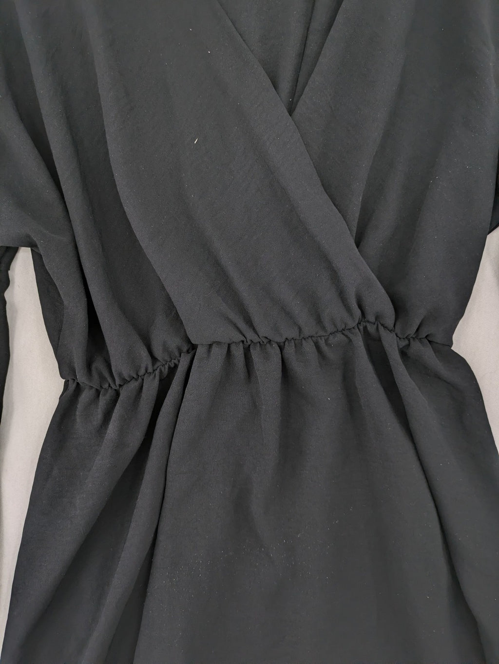 Bella black wrap blouse with deep V-neck and ruffled long sleeves.