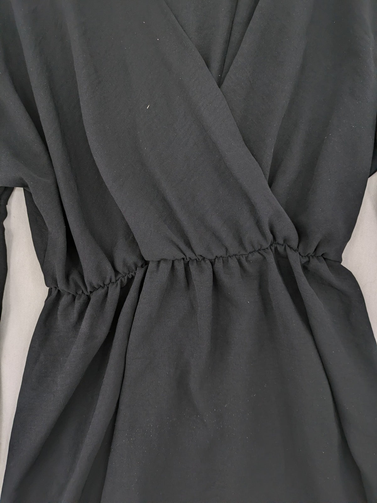 Bella black wrap blouse with deep V-neck and ruffled long sleeves.