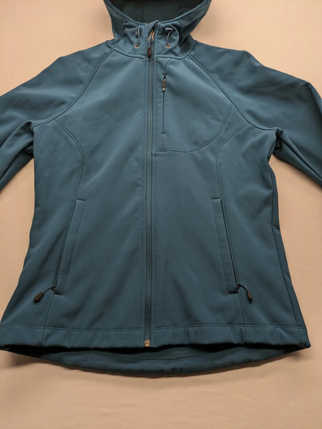 Kirkland Signature blue softshell jacket with hood, fleece lining, and zippered pockets.