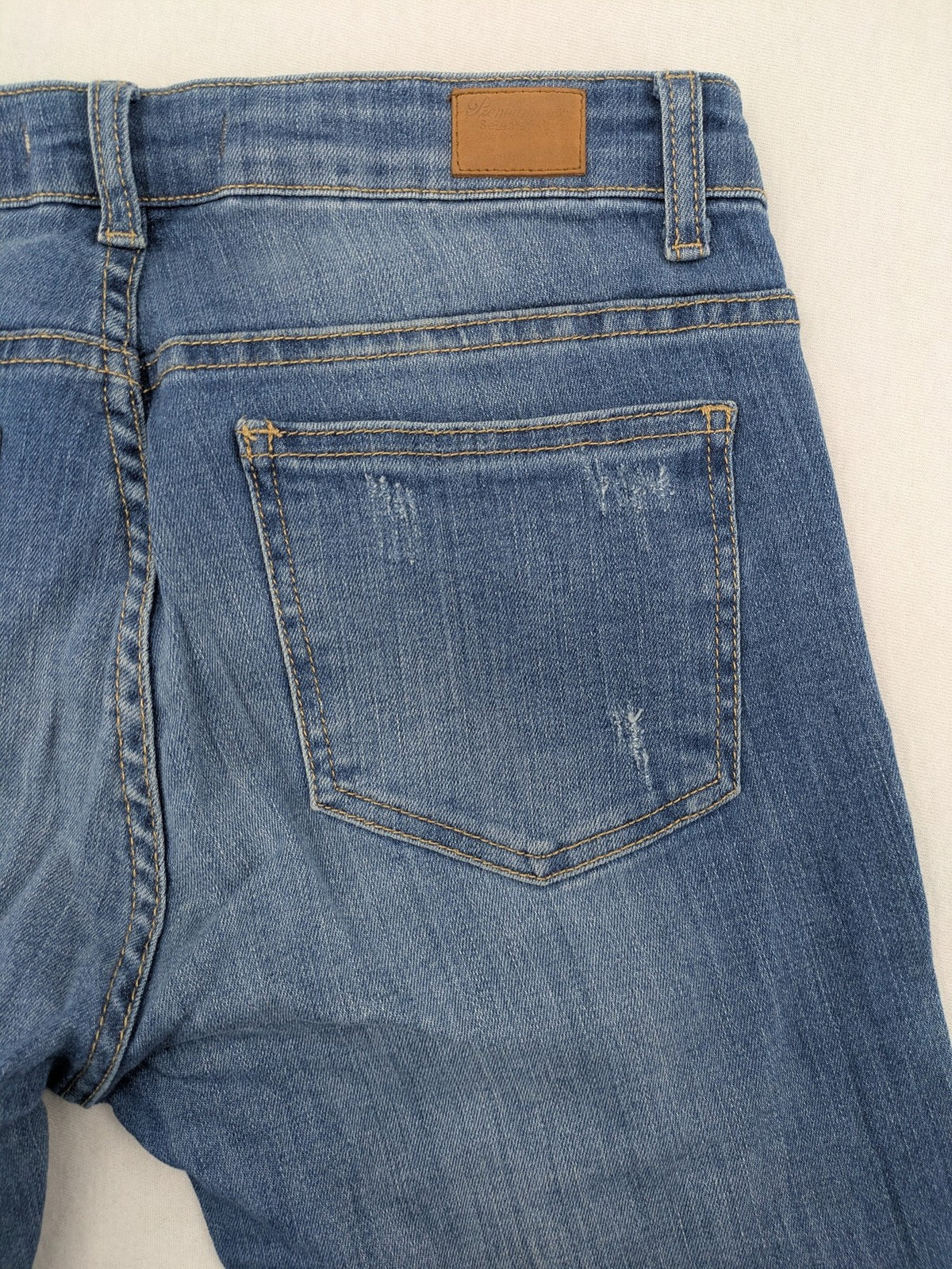 Tally Weijl blue bootcut jeans with distressed knees and raw hem detail.