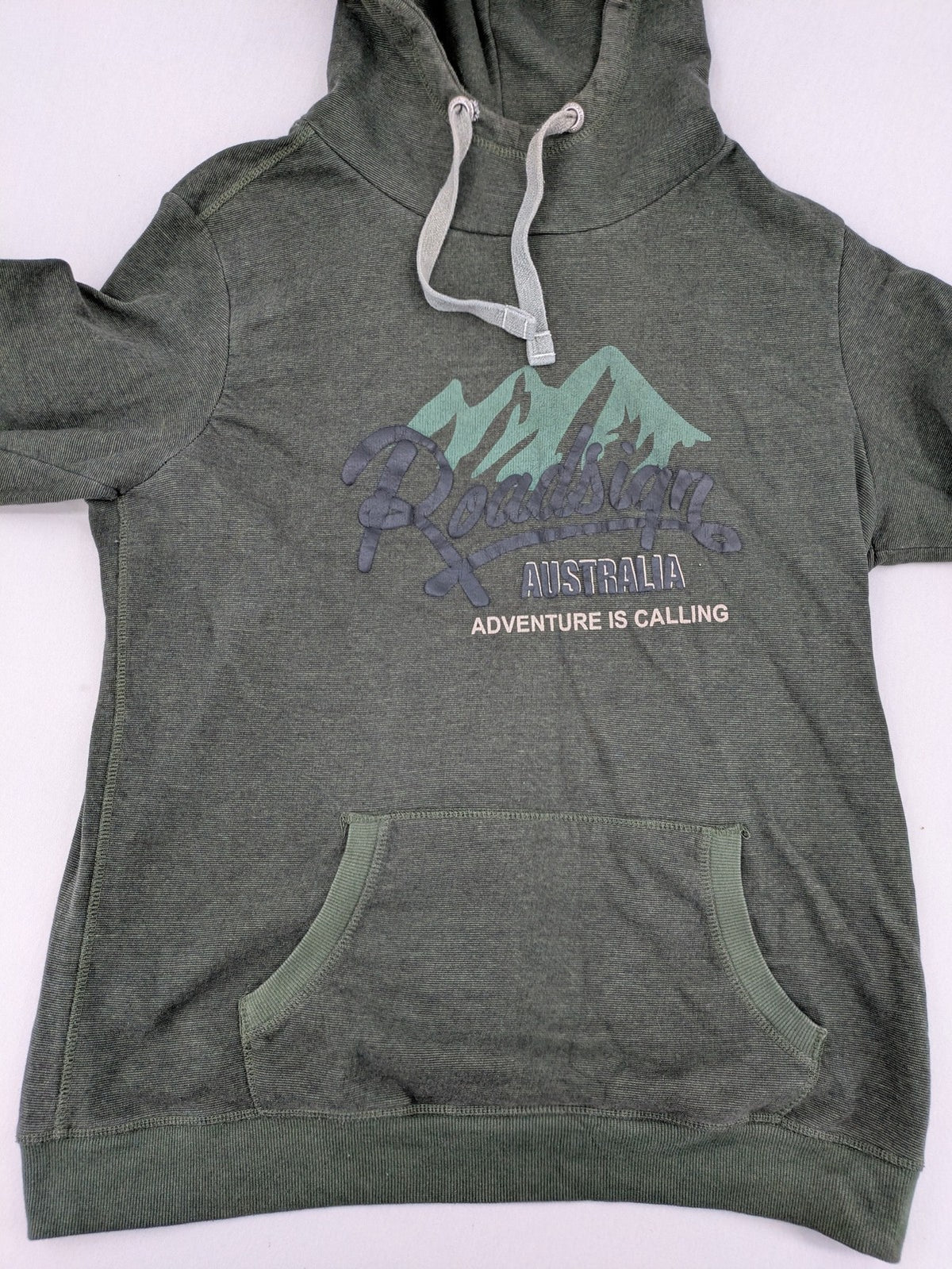 Roadsign Australia green hoodie with mountain graphic print and logo patch on sleeve.