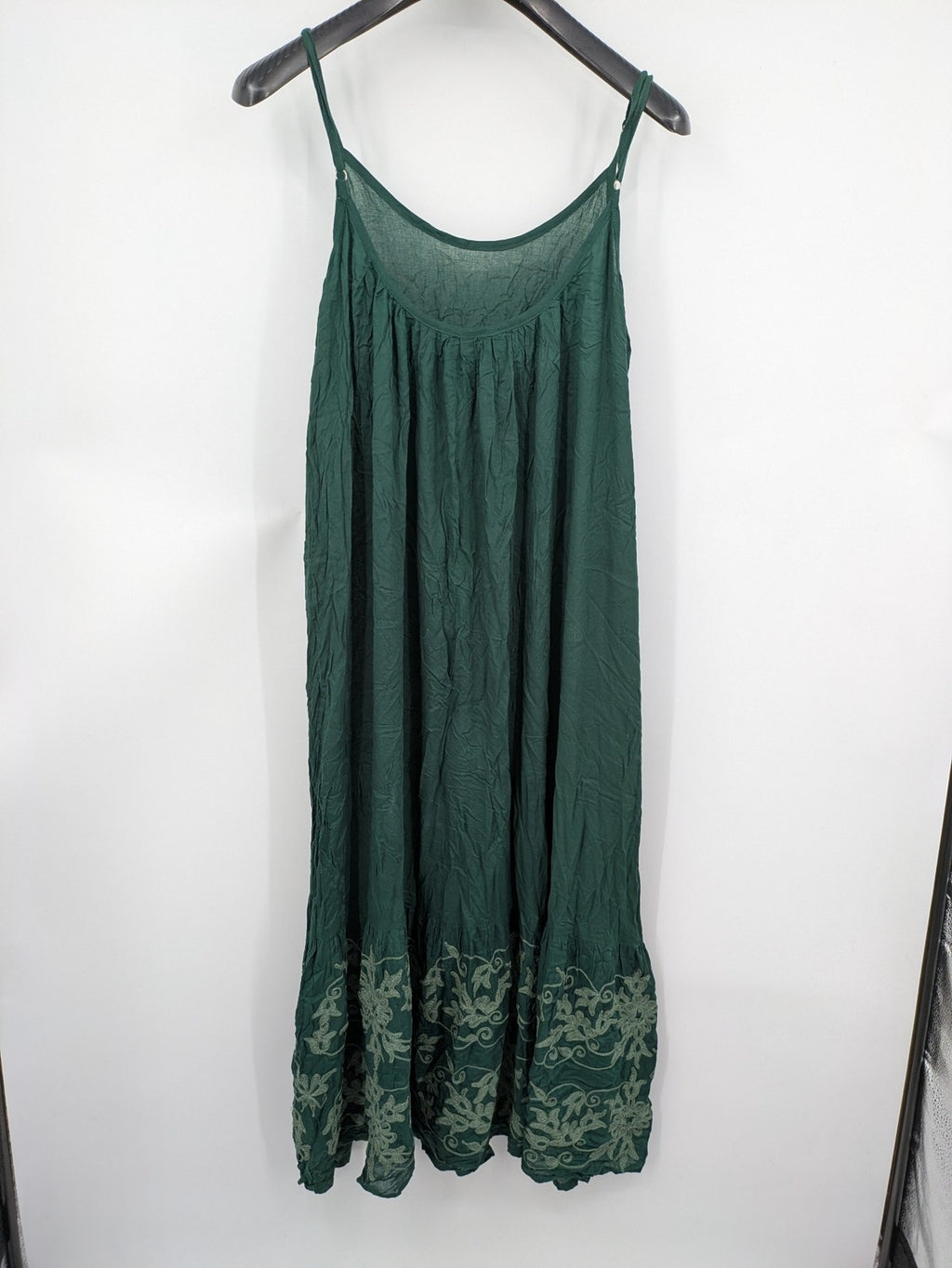Boho green maxi dress with floral embroidery along tiered hem and adjustable spaghetti straps.