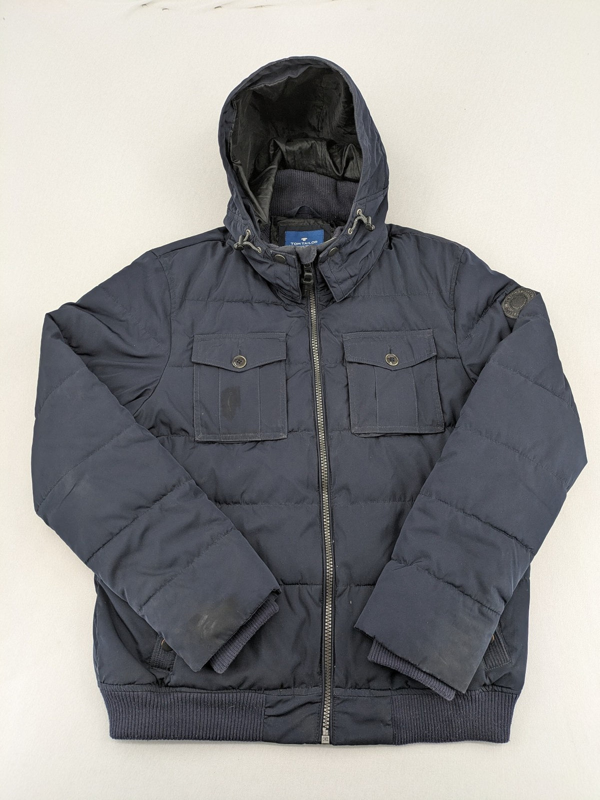 Tom Tailor navy puffer jacket with quilted design and adjustable hood, featuring multiple pockets.