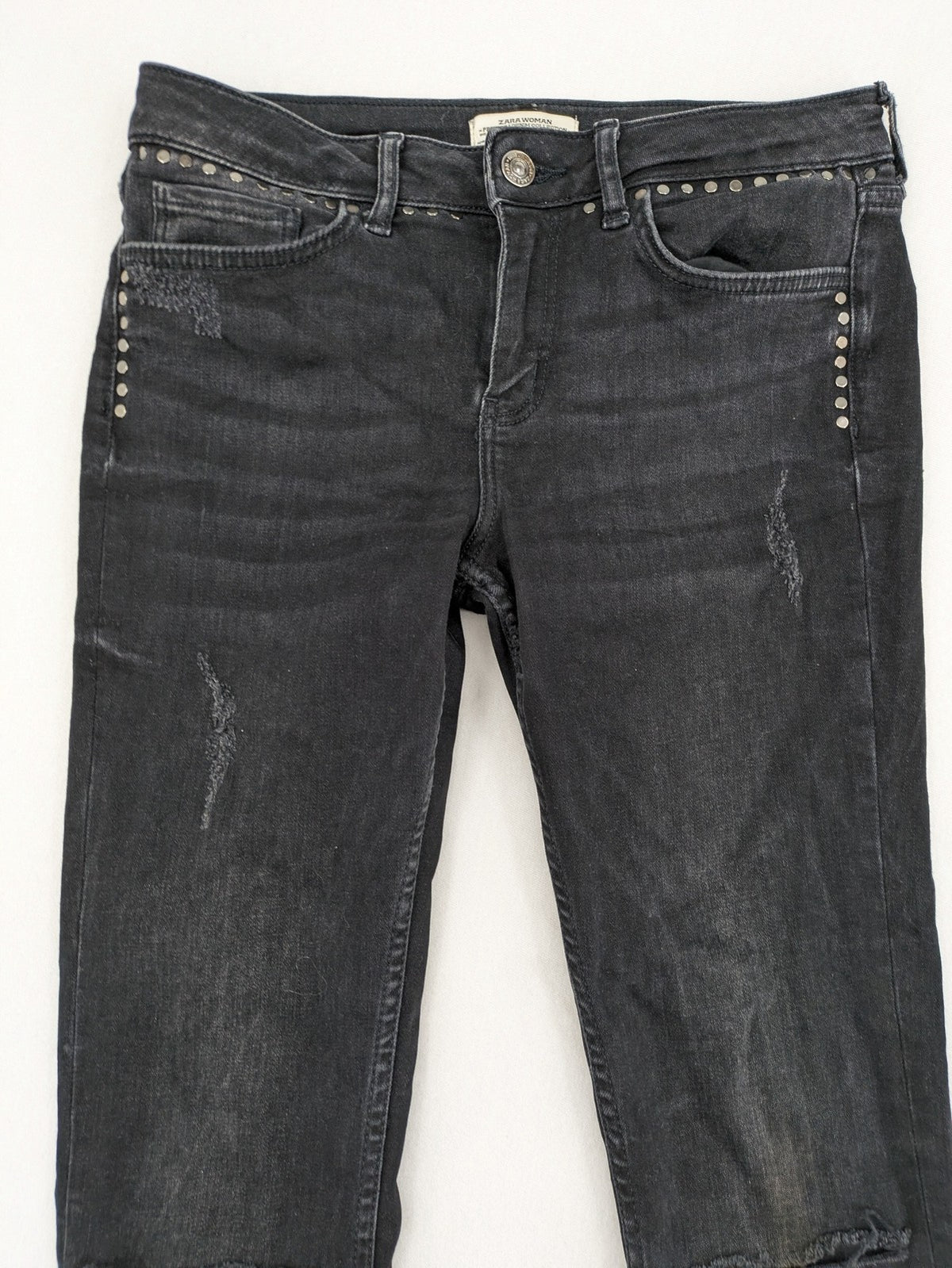 Zara Woman black skinny jeans with distressed details, silver studs, and frayed hem.
