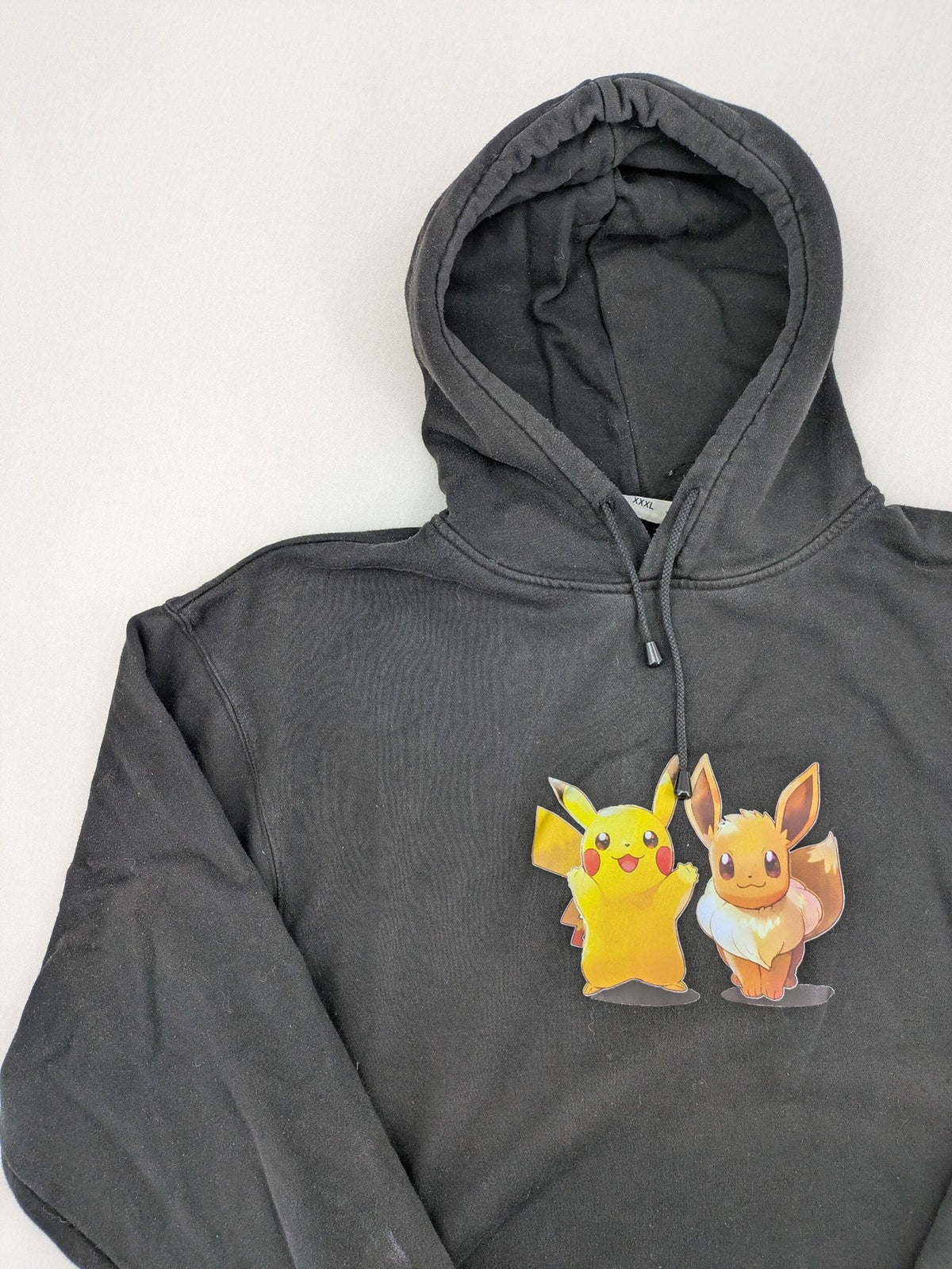 Pokémon black hoodie featuring colorful Pikachu and Evoli graphic, classic pullover style.