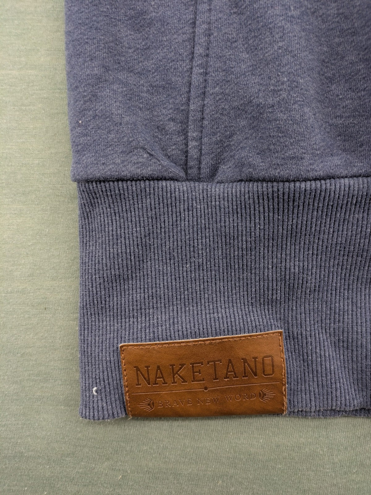 Naketano grey turtle neck jumper with thick drawstring and leather logo appliqué.