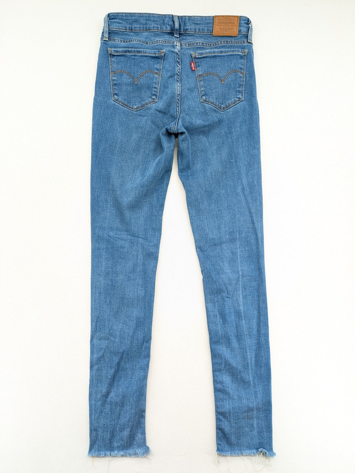 Levi's blue skinny jeans with raw hem, classic five-pocket design, and zip fly.