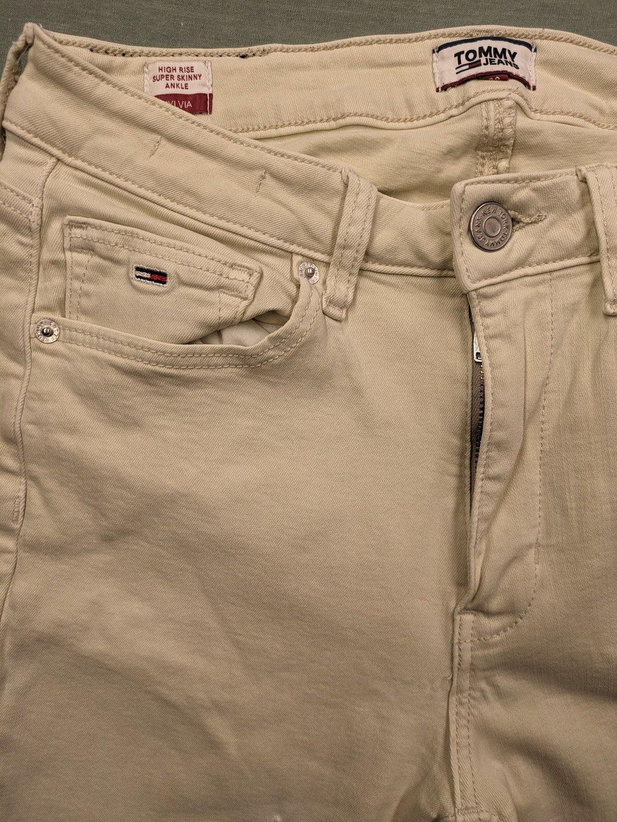 Tommy Jeans beige high rise skinny ankle jeans with logo patch and stretch fabric.