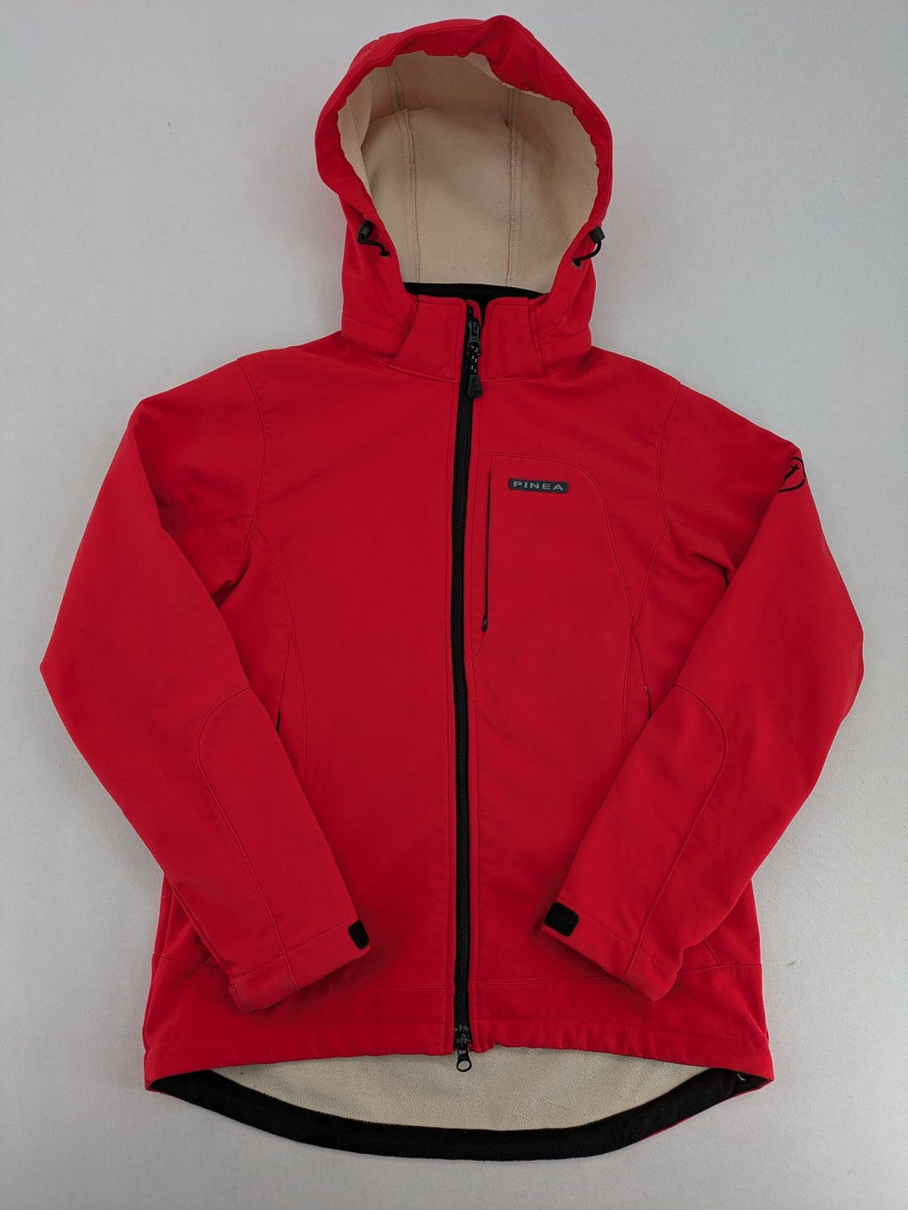 Pinea red softshell jacket with adjustable hood and fleece lining, multiple zippered pockets.