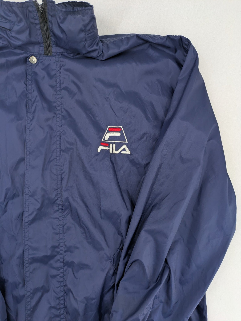 Fila navy windbreaker jacket with large embroidered logo on chest and back.
