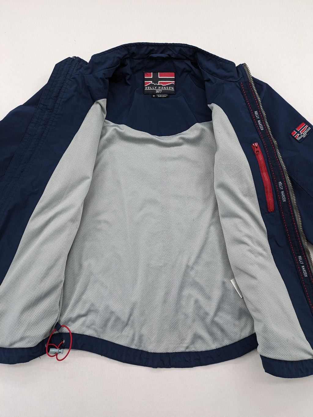 Helly Hansen navy jacket with red accents and logo, full zip, breathable mesh lining.