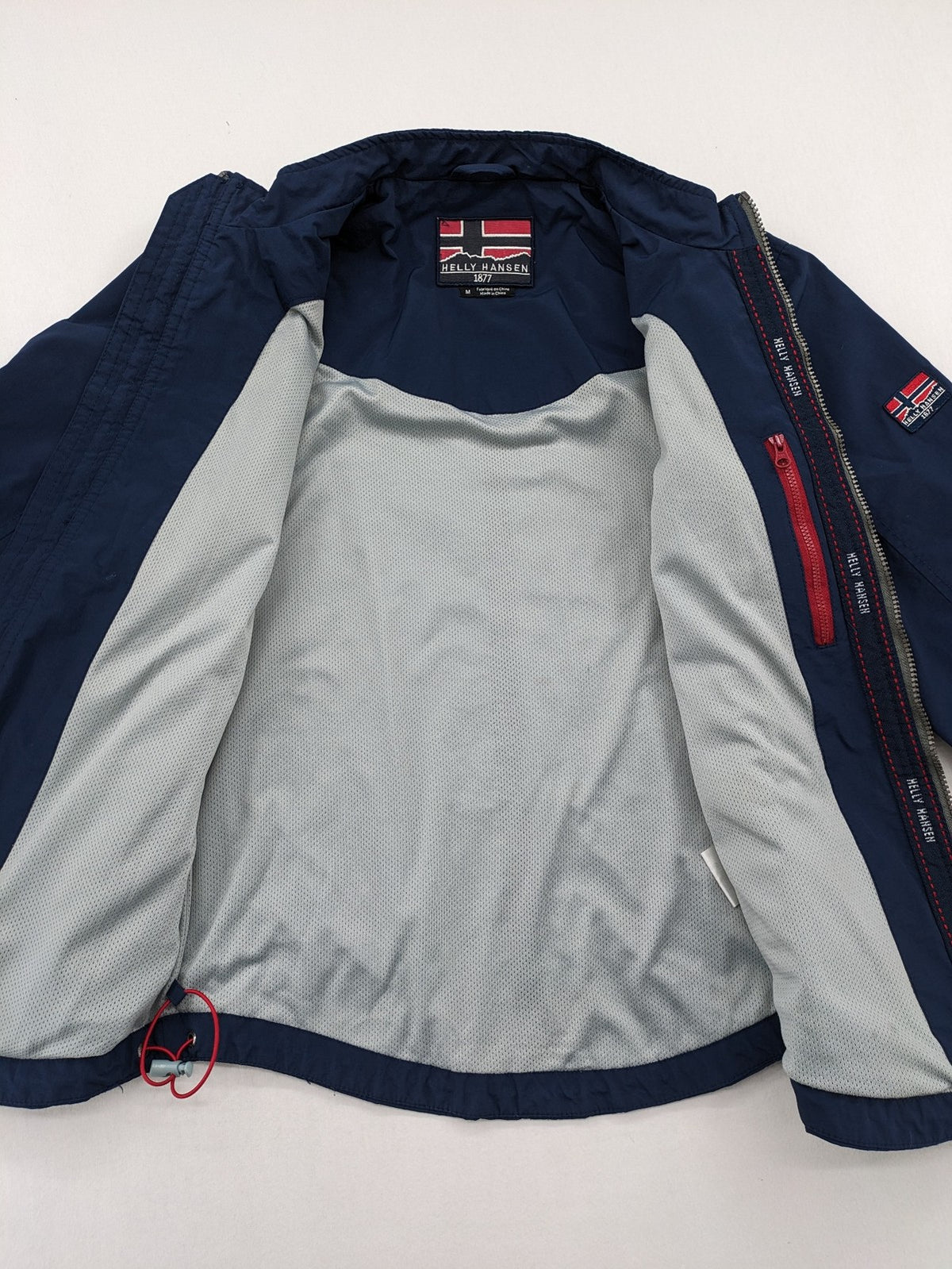 Helly Hansen navy jacket with red accents and logo, full zip, breathable mesh lining.