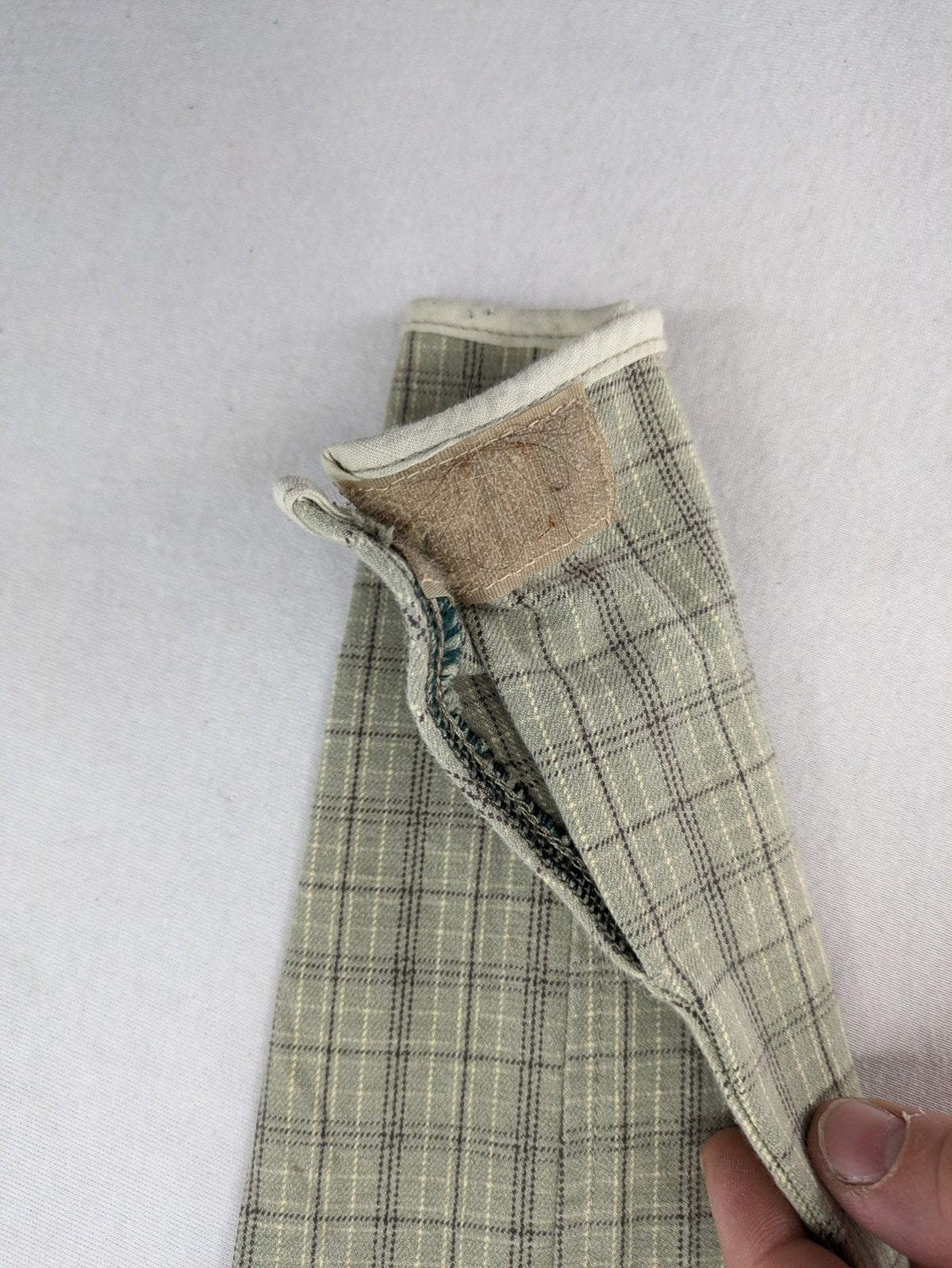 Jodhpur beige and grey riding pants with green check pattern and knee patches.