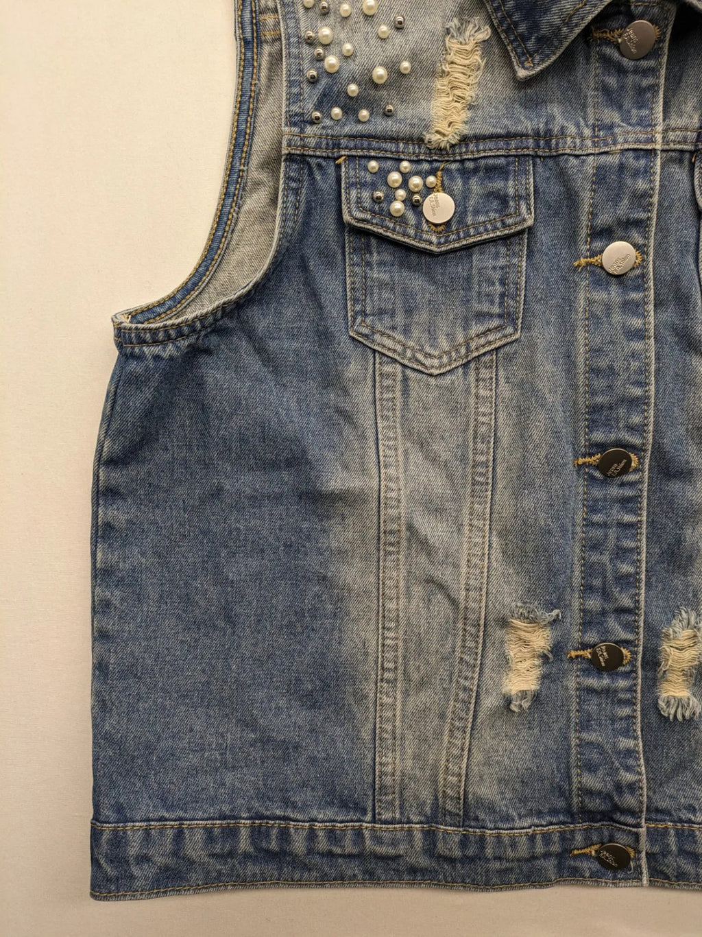 Damen Jeansjacke blau ärmellos mit Perlenverzierung, distressed Details und Knopfleiste.