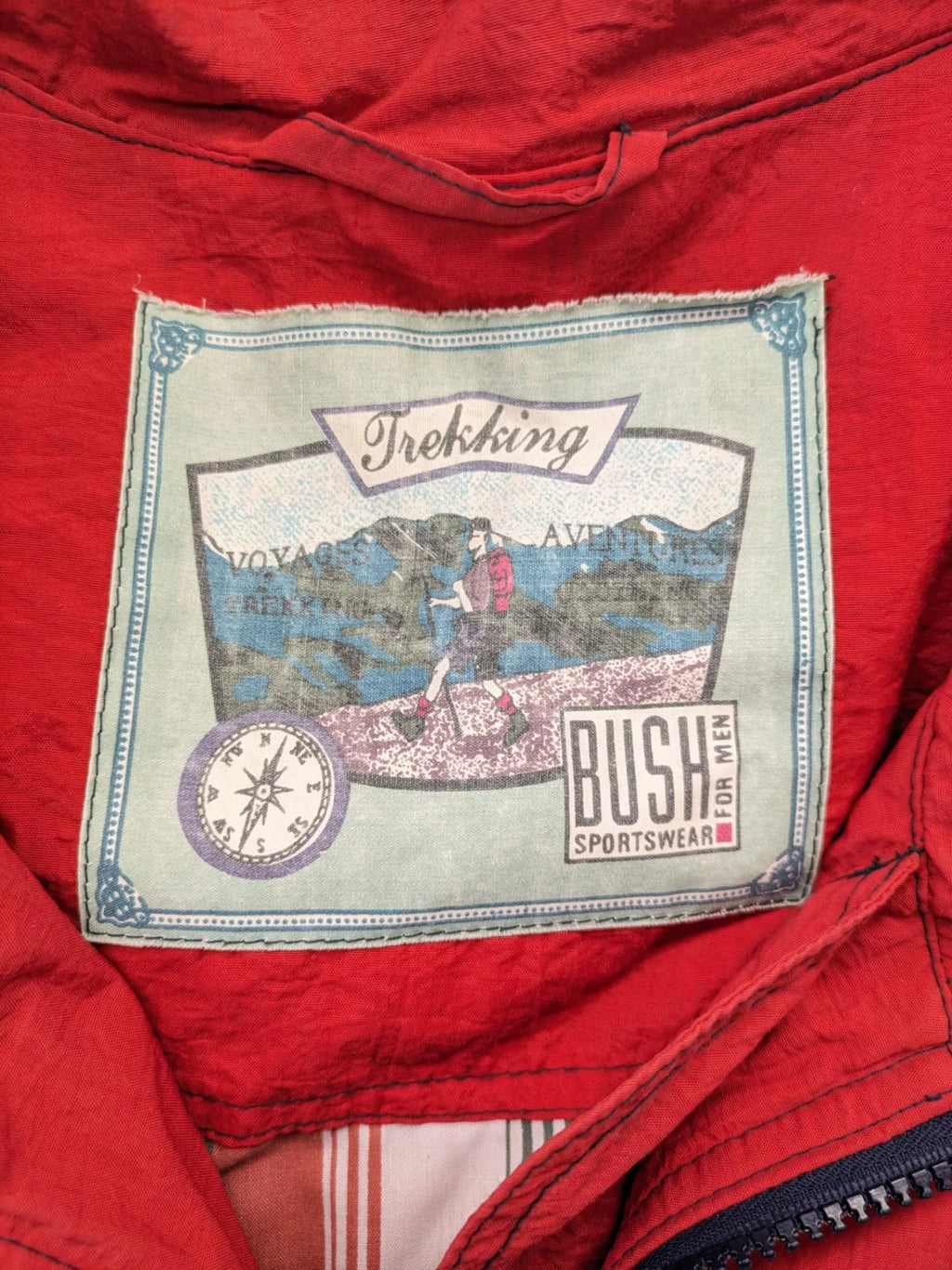 Bush Sportswear red trekking jacket with front zipper, multiple pockets, and striped lining.