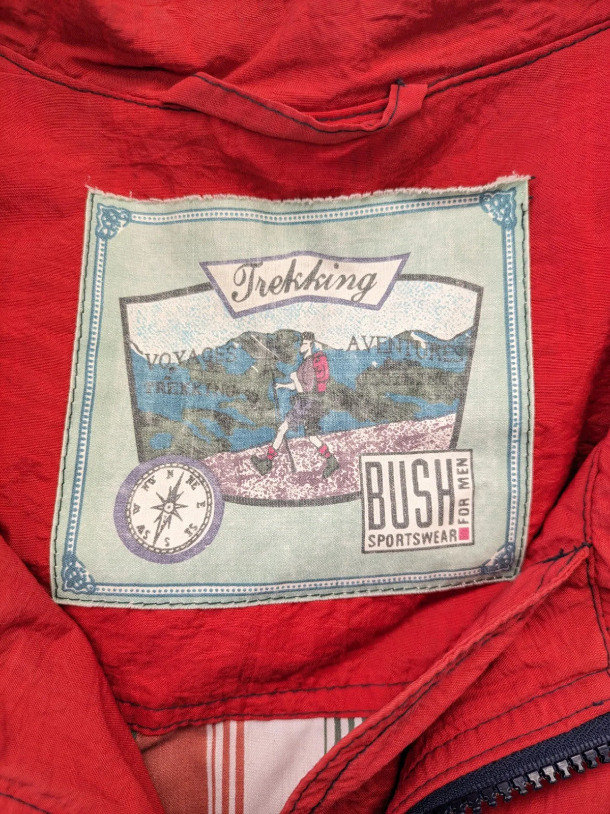 Bush Sportswear red trekking jacket with front zipper, multiple pockets, and striped lining.