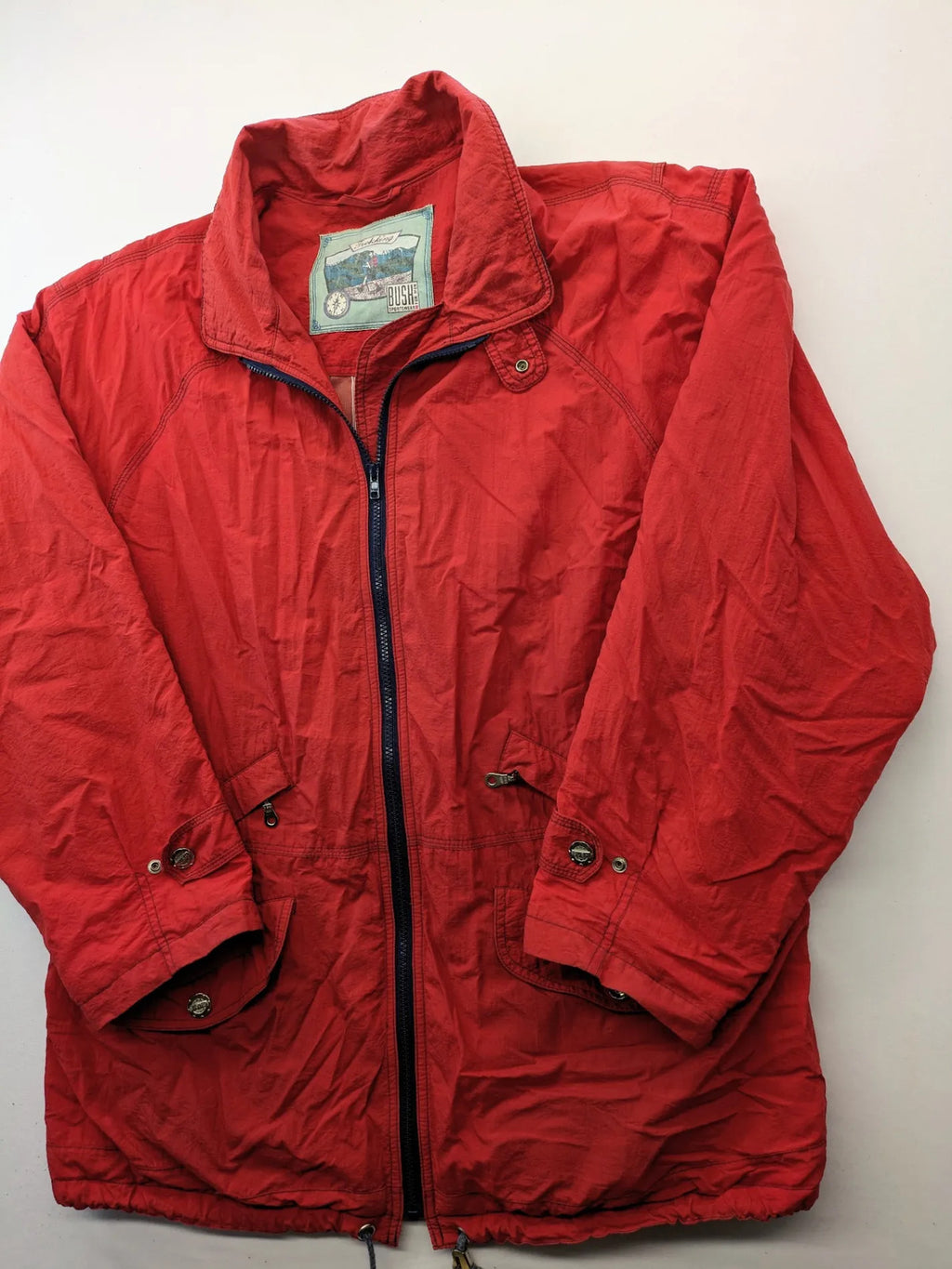 Bush Sportswear red trekking jacket with front zipper, multiple pockets, and striped lining.
