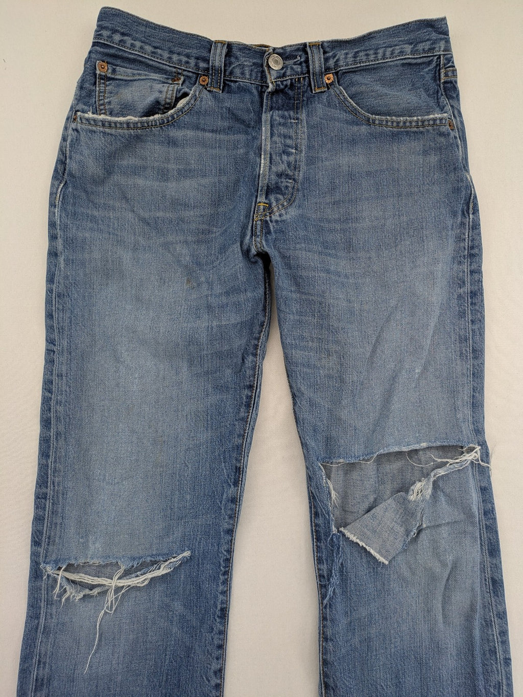 Levi's blue straight jeans with button-fly and distressed knee rips.
