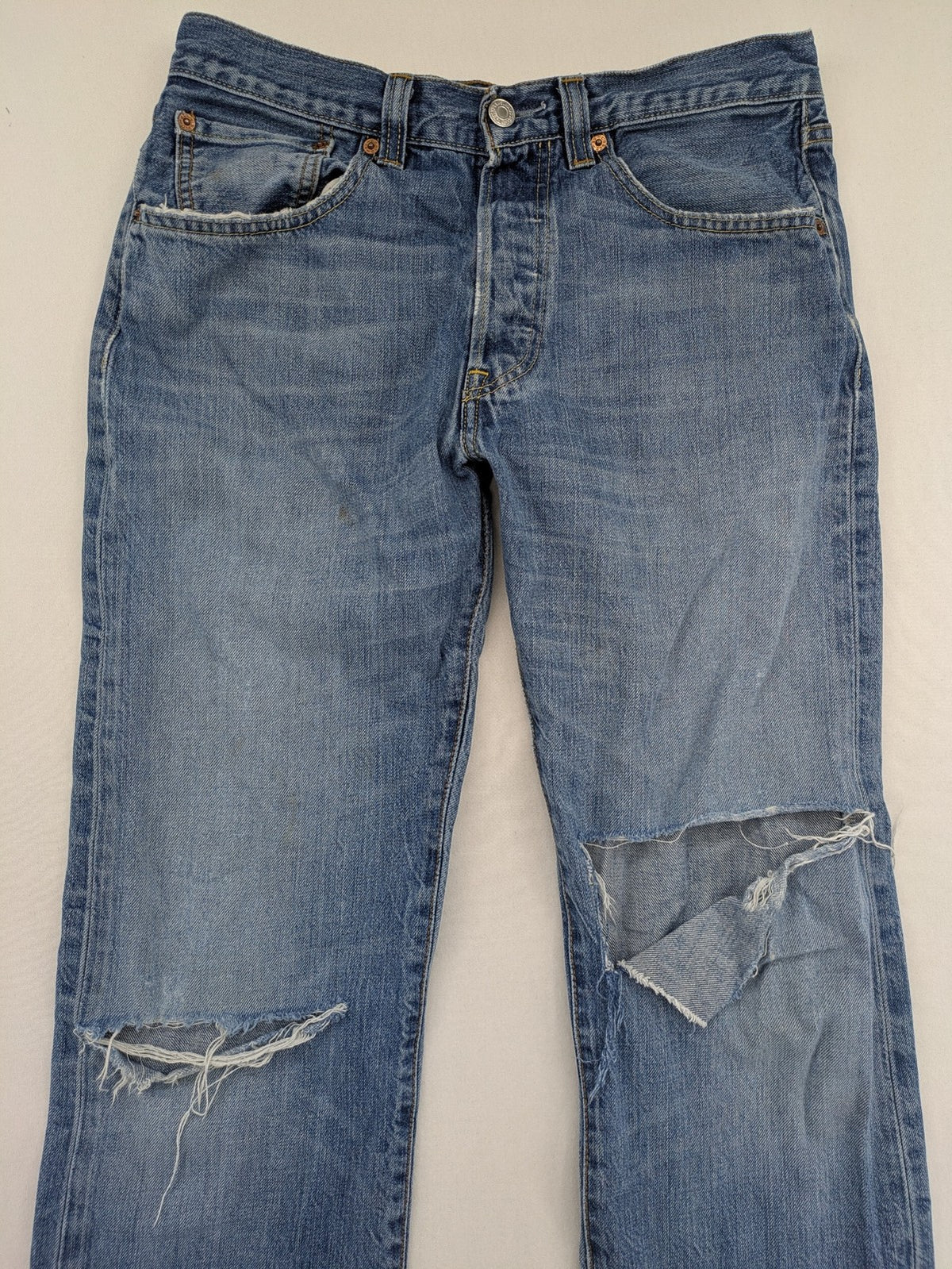 Levi's blue straight jeans with button-fly and distressed knee rips.
